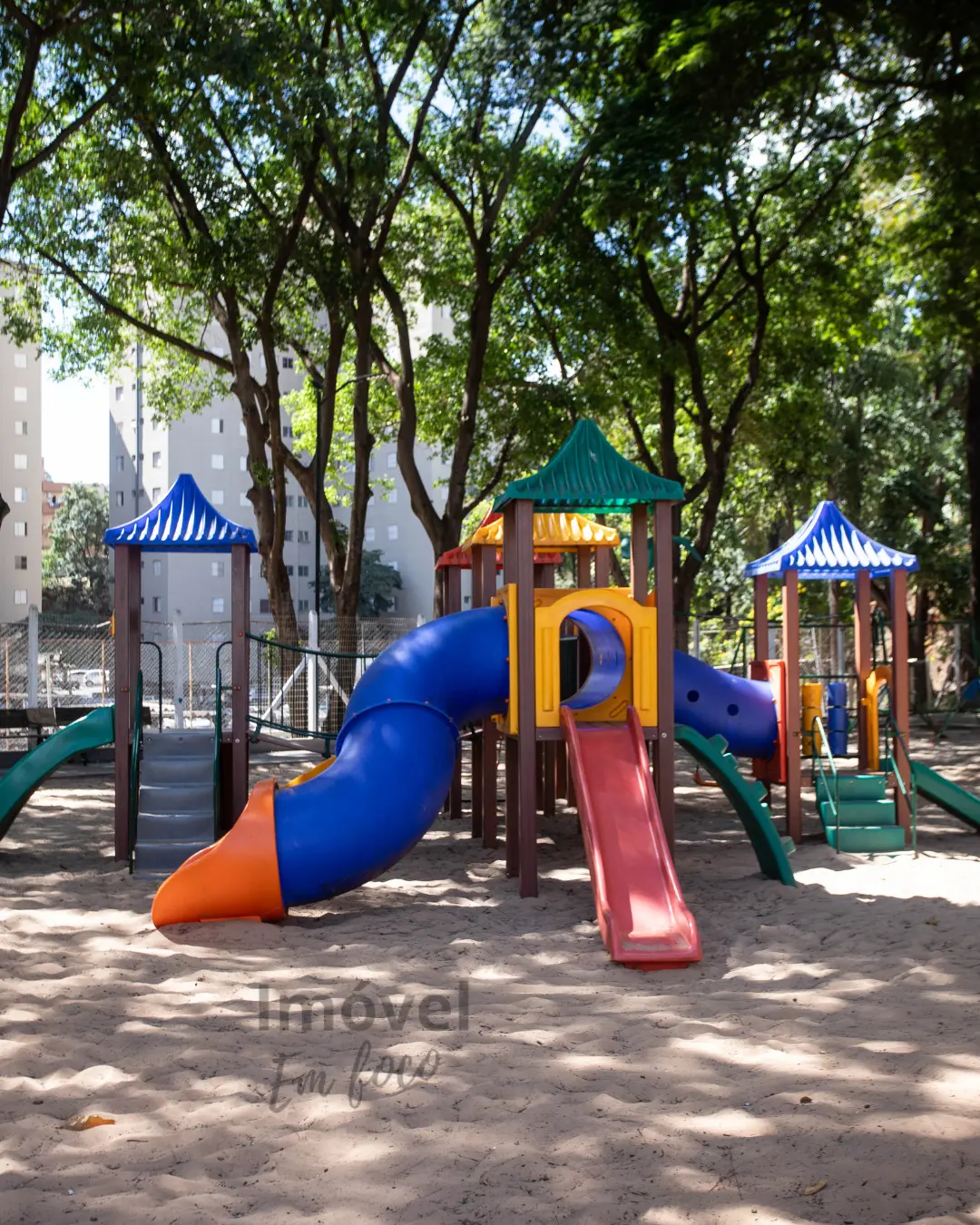 Área infantil externa cercada de muito verde.
